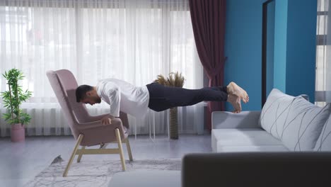 Sportsman-doing-push-ups-briskly-using-sofa-and-armchair.